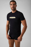 Camiseta Guess negra de cuello redondo con logo dorado en el pecho, sobre modelo