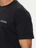 Detalle del logo Guess blanco en el pecho de la camiseta negra